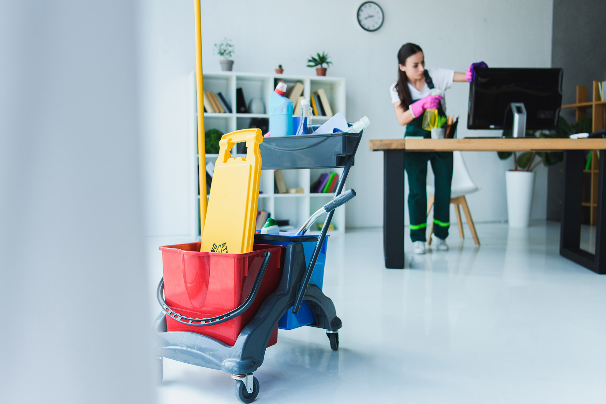 Professional cleaner tidying office desk